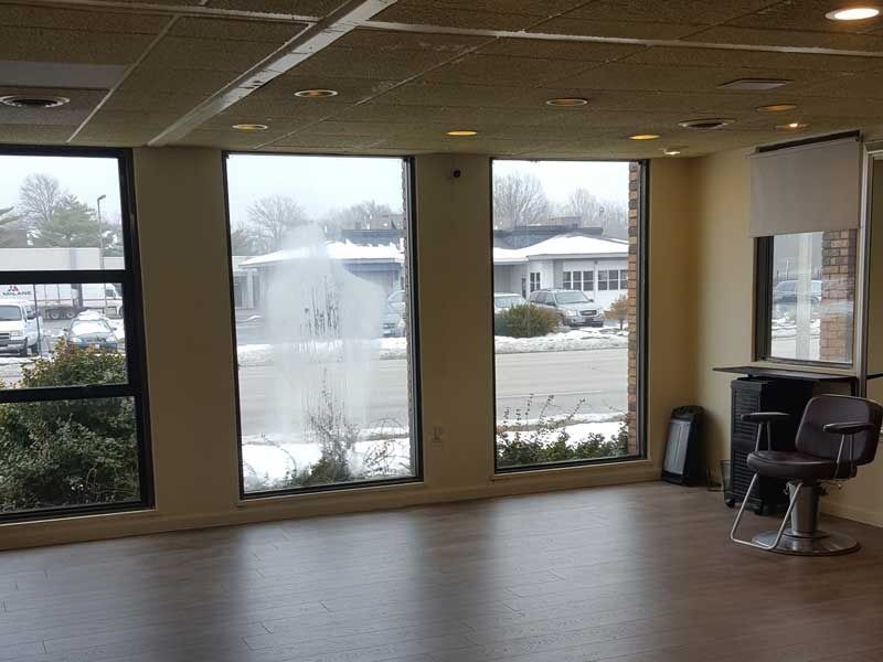 An empty room with a barber chair and a lot of windows
