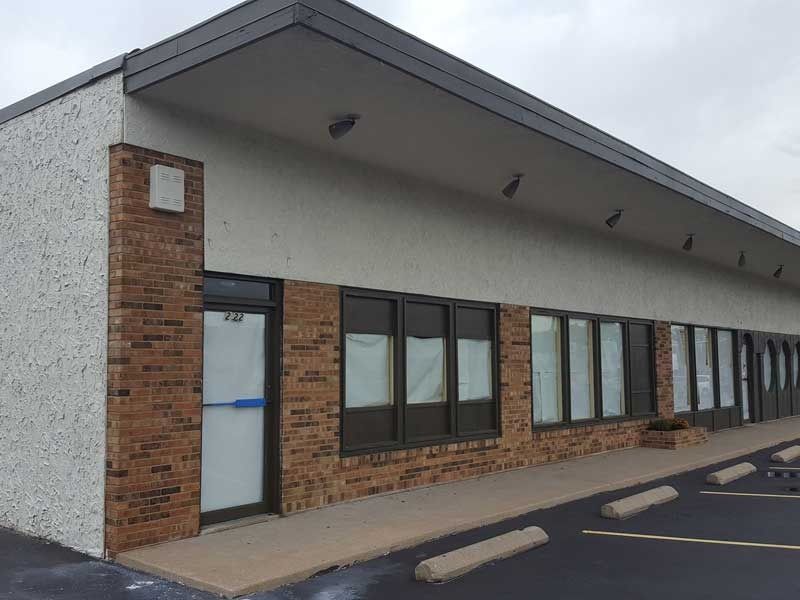 A brick building with a lot of windows and a parking lot in front of it.