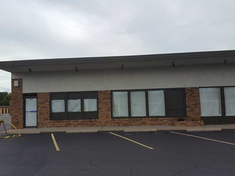 A brick building with a lot of windows and a parking lot in front of it.