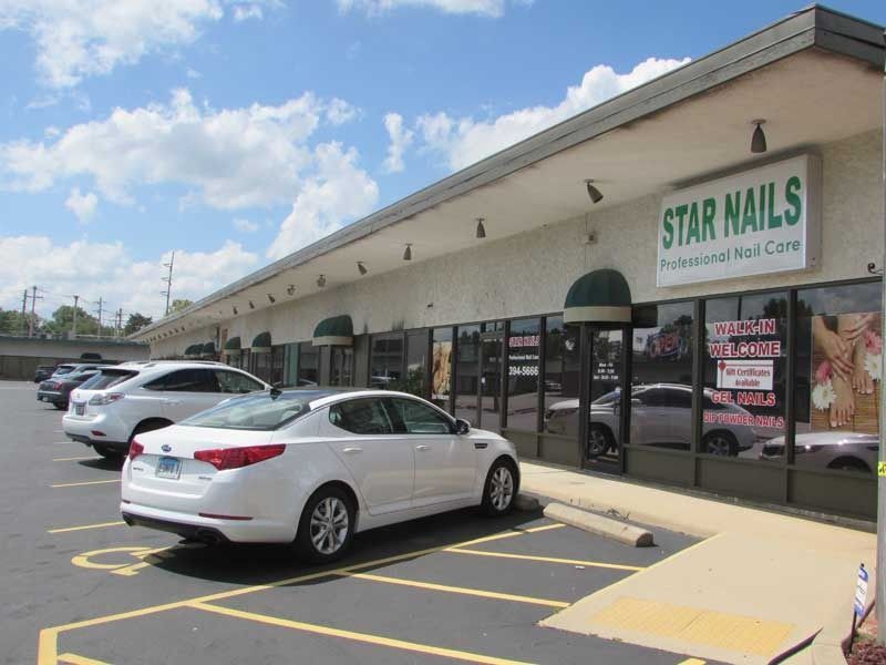 A white car is parked in front of a building that says star nails