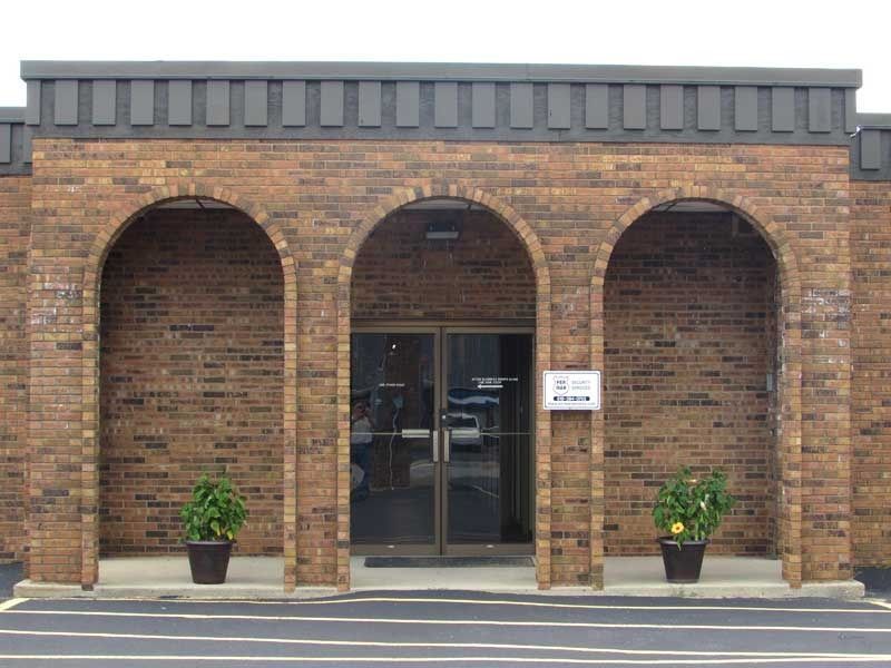 A brick building with arches and potted plants in front of it
