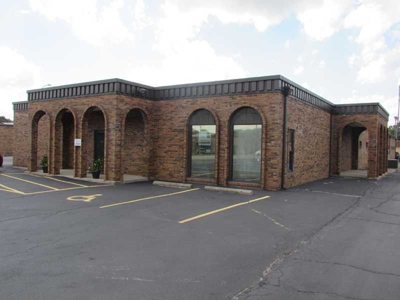 A large brick building with arches and a parking lot in front of it.