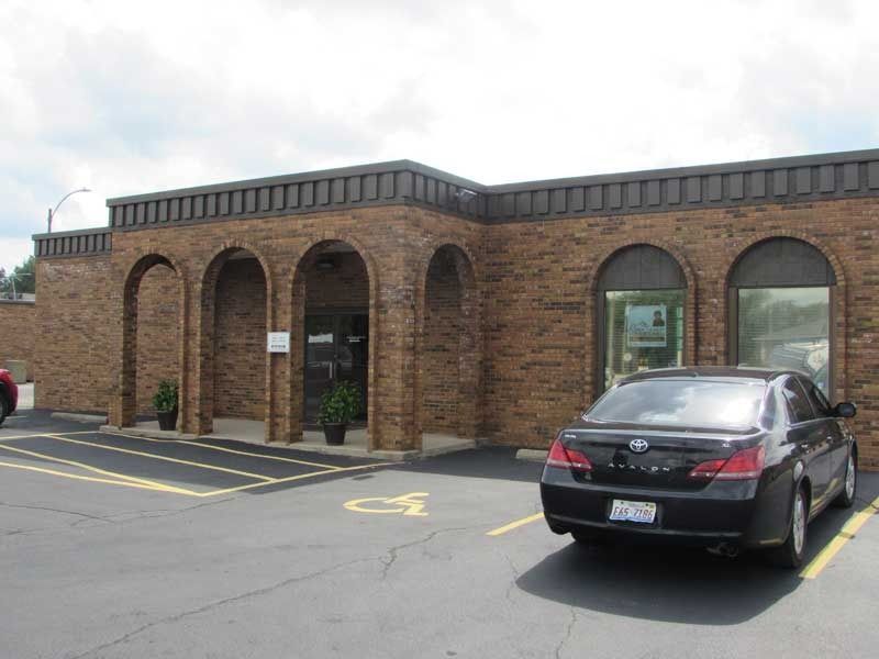 A black car is parked in front of a brick building.