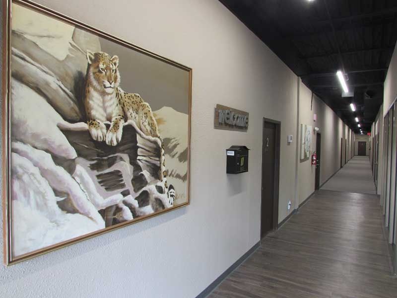 A long hallway with a painting of a leopard on the wall.