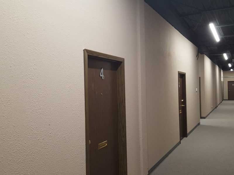 A long hallway with a door in the middle of it.