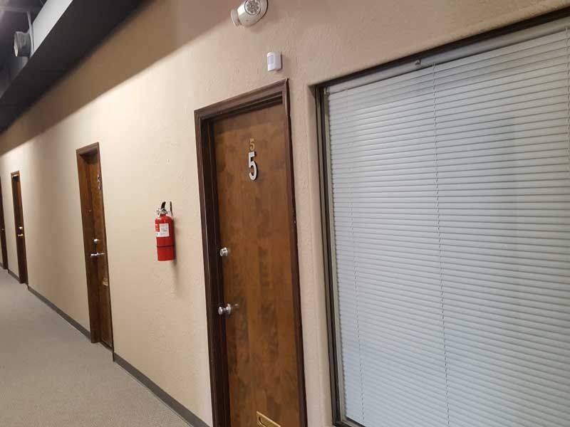 A hallway with a fire extinguisher on the wall and a door with the number 6 on it