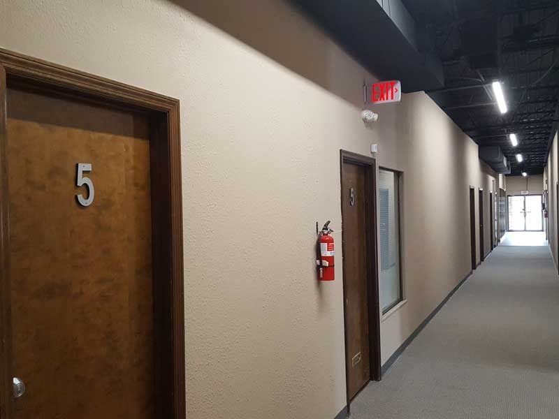 A hallway with a fire extinguisher on the wall and a door with the number 5 on it.