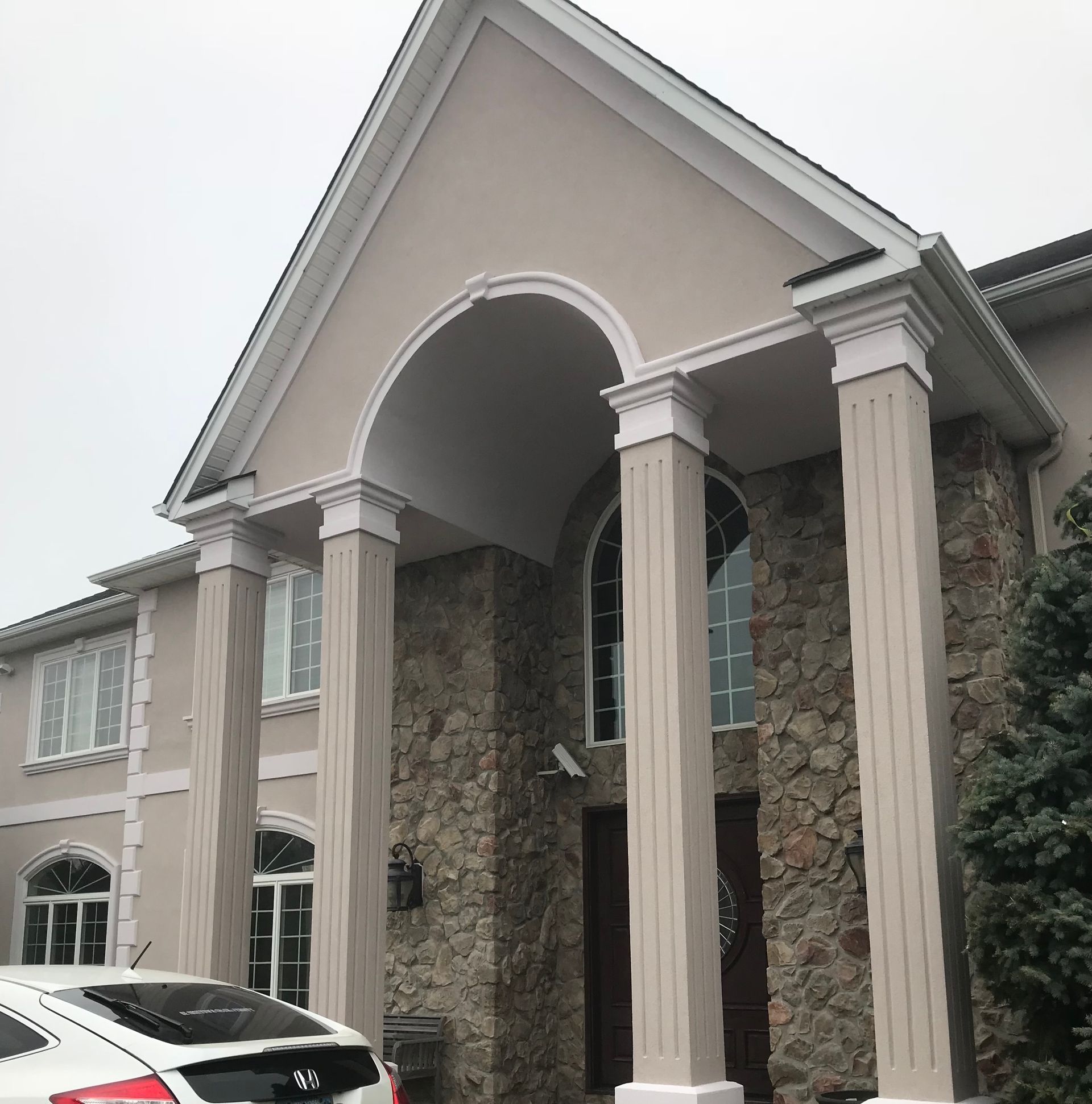 A car is parked in front of a large house