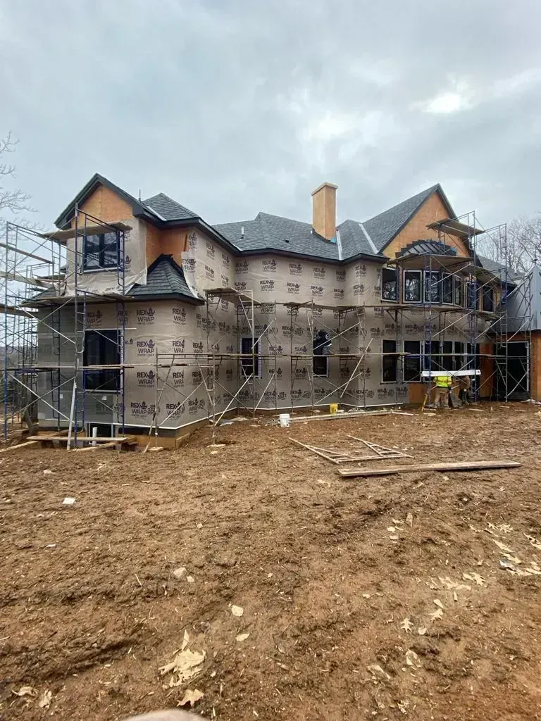 A large house is being built in a dirt field.