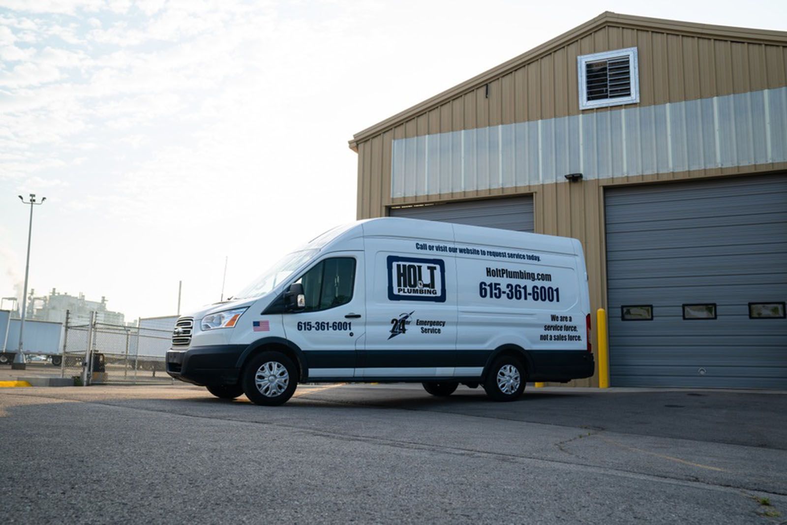 White service van with company logo parked near a beige industrial building.