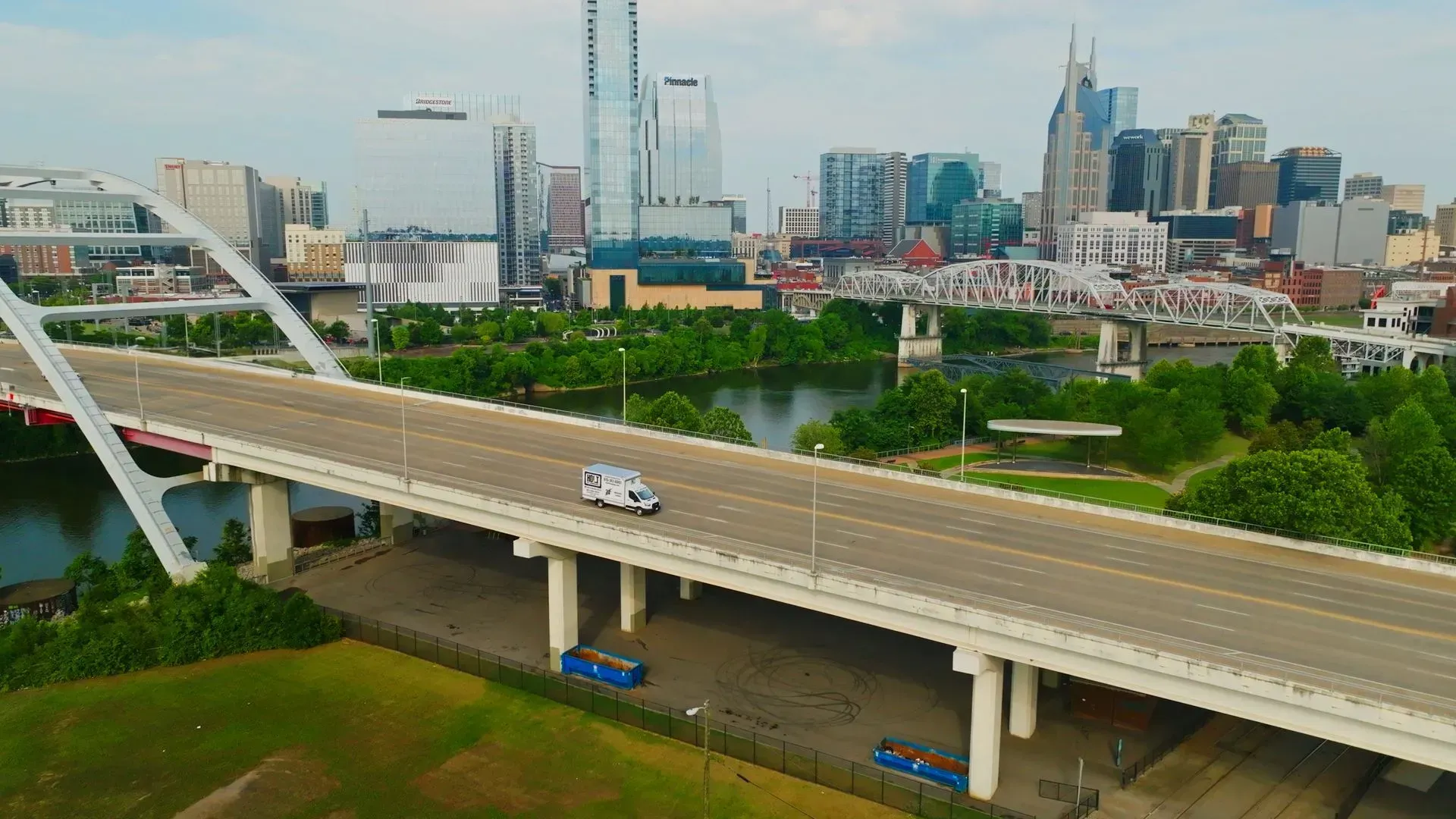 An ambulance drives on a bridge over a river, with the Nashville skyline in the background.