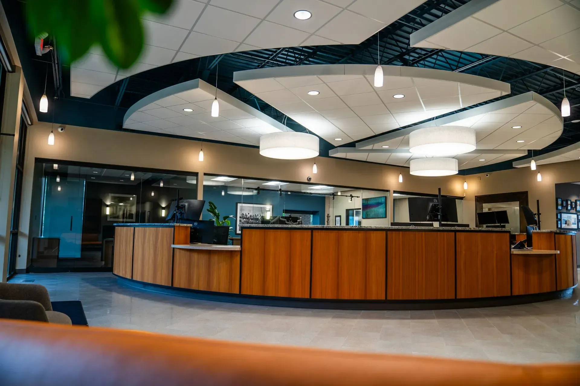 Reception area with wooden counter, overhead lights, and glass windows.