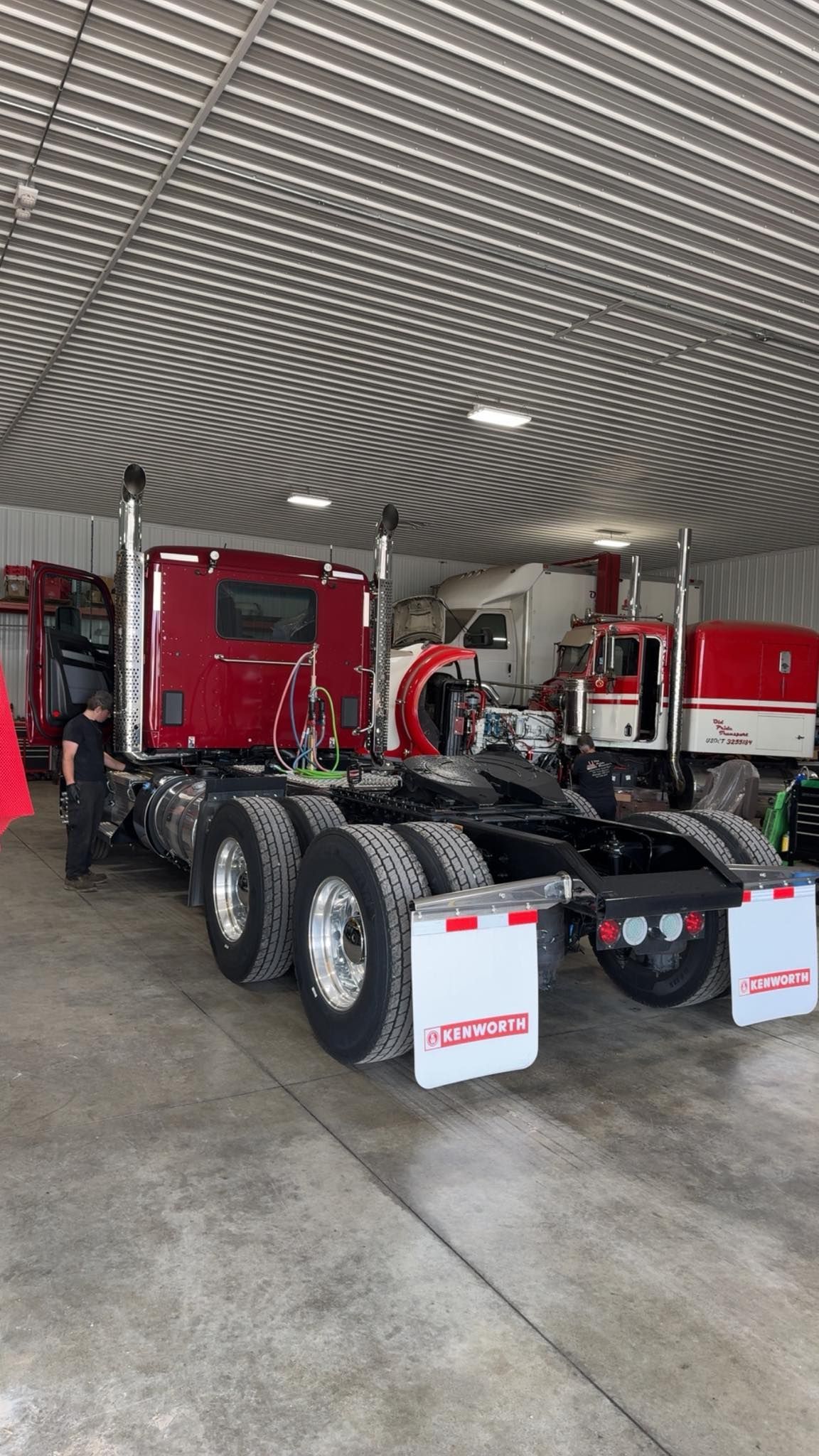 Red semi-truck parked inside a garage, with shiny chrome wheels and a detailed interior visible.