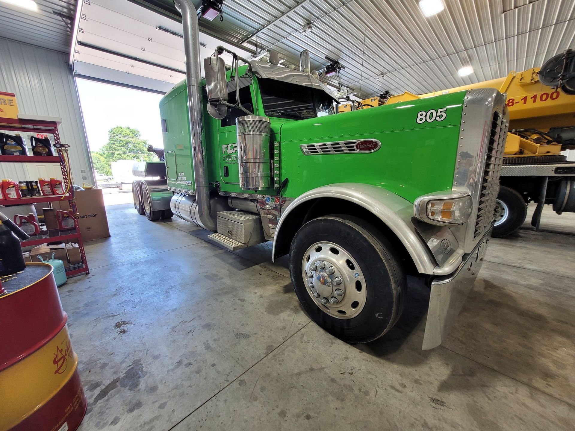 Green semi-truck in a garage.
