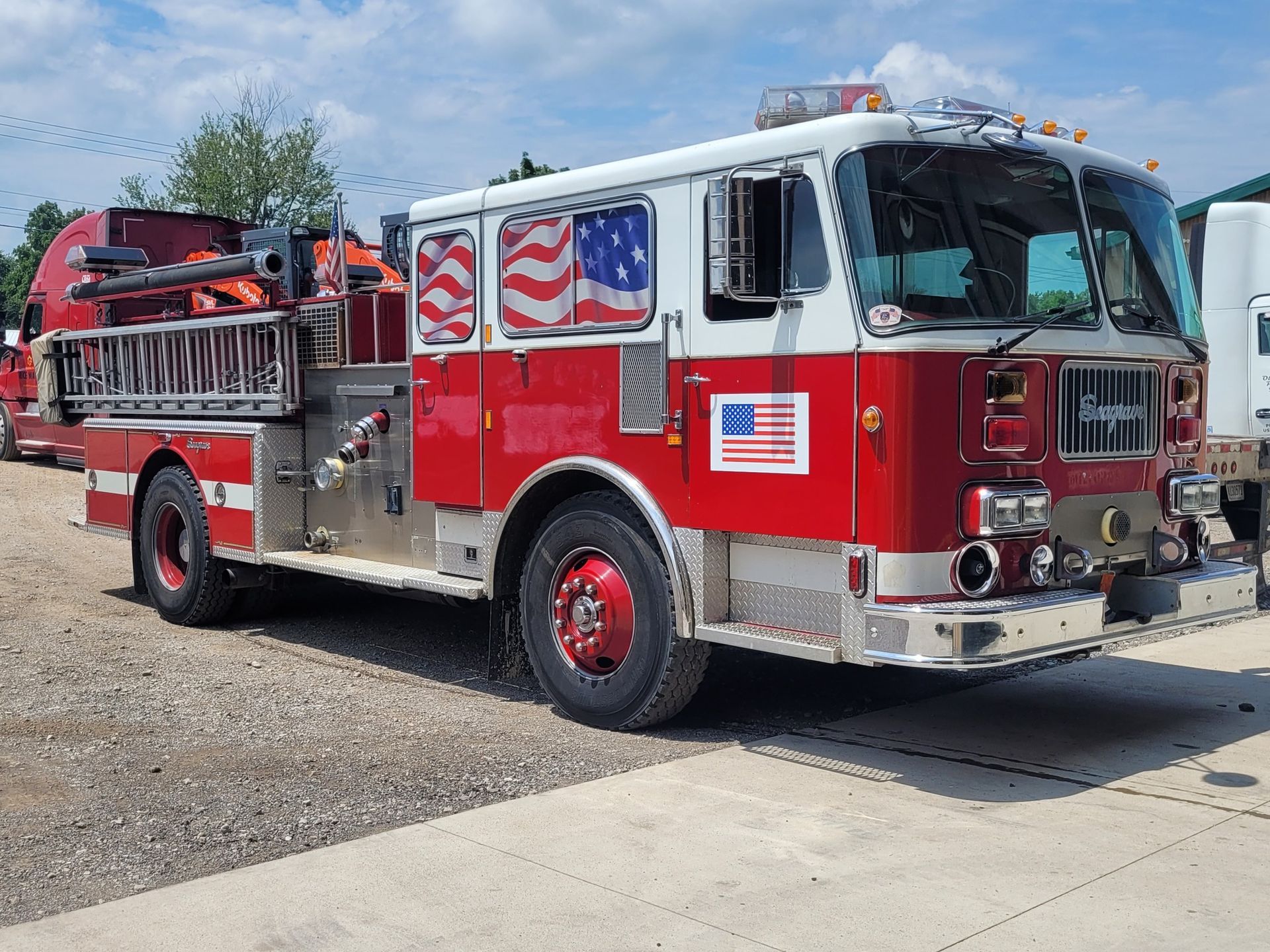 Red and white fire truck with an American flag design on its side, parked outside.