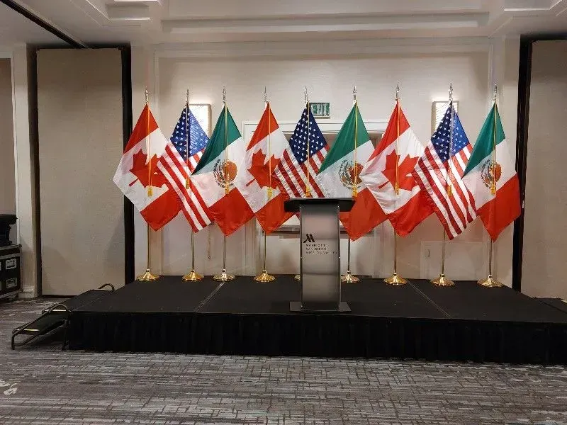 Flags of Canada, the U.S., and Mexico arranged on stage with a podium.
