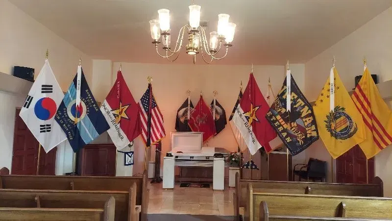 Flags of various nations and military branches displayed in a room with pews.