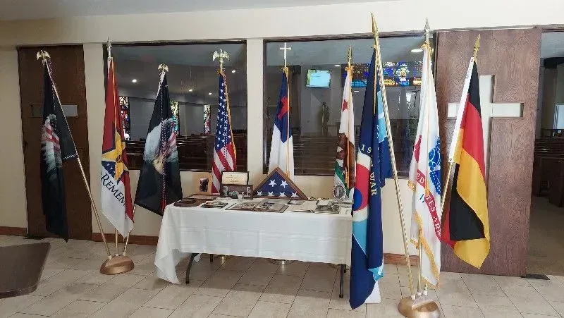 Flags of the U.S. military, a folded American flag, and memorabilia on a table; room setting.