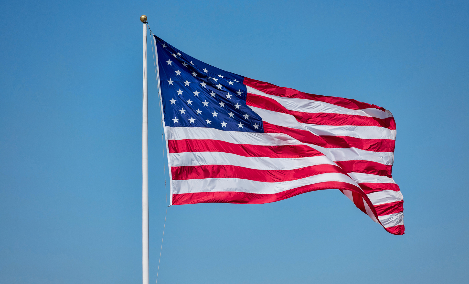 American flag waving in the wind against a clear blue sky.
