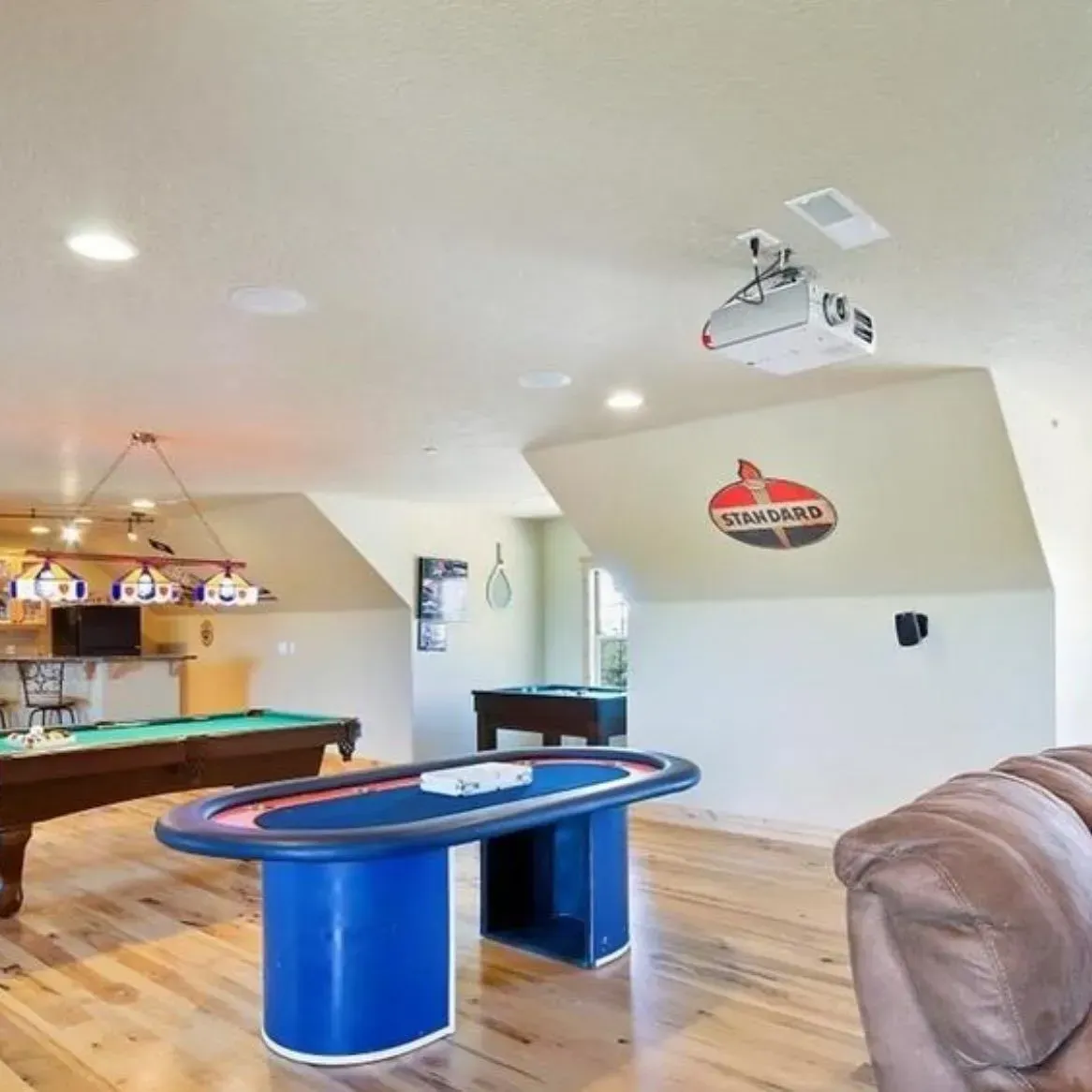 Game room with pool table, poker table, projector, and seating.