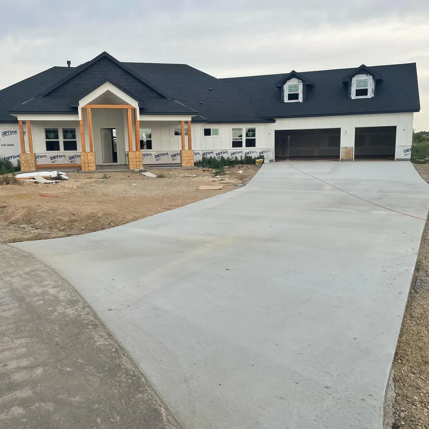 New house under construction with a concrete driveway and two-car garage.