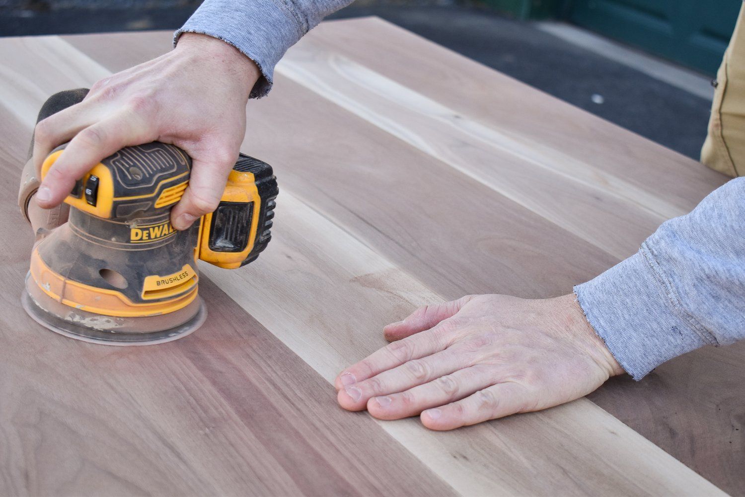 A person is sanding a piece of wood with a sander.
