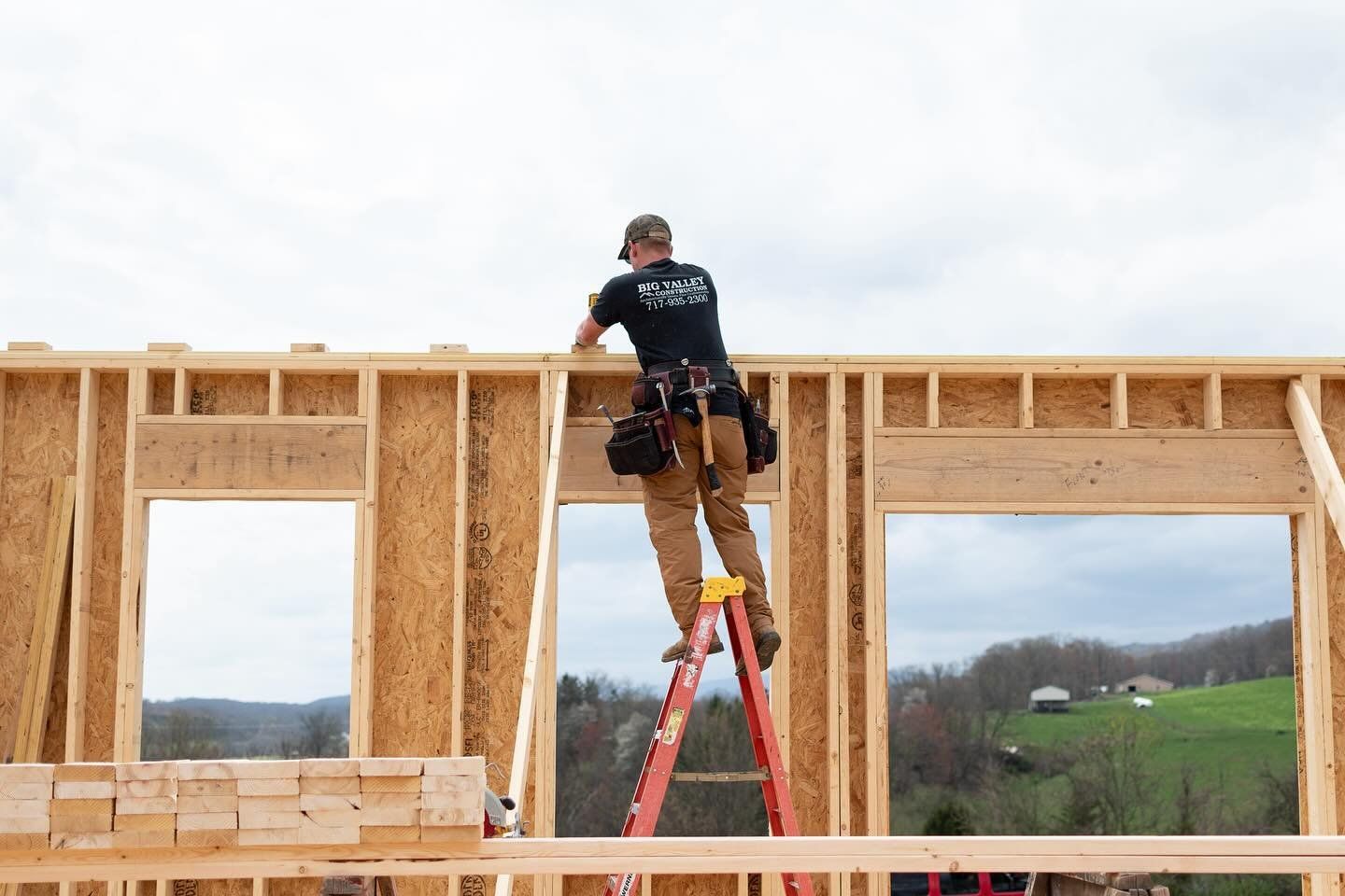 A man is standing on a ladder on top of a wooden structure.