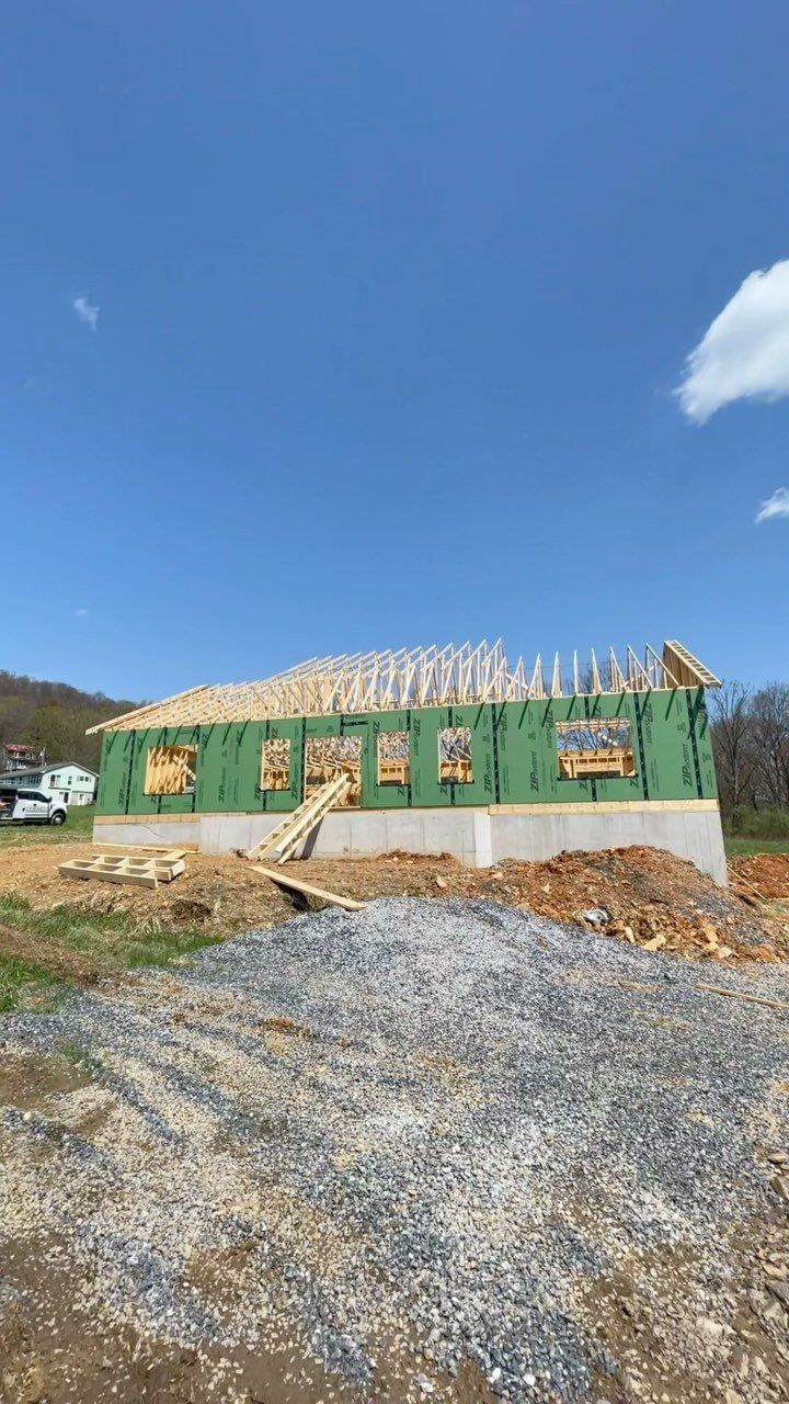 A house is being built in a field with a blue sky in the background.