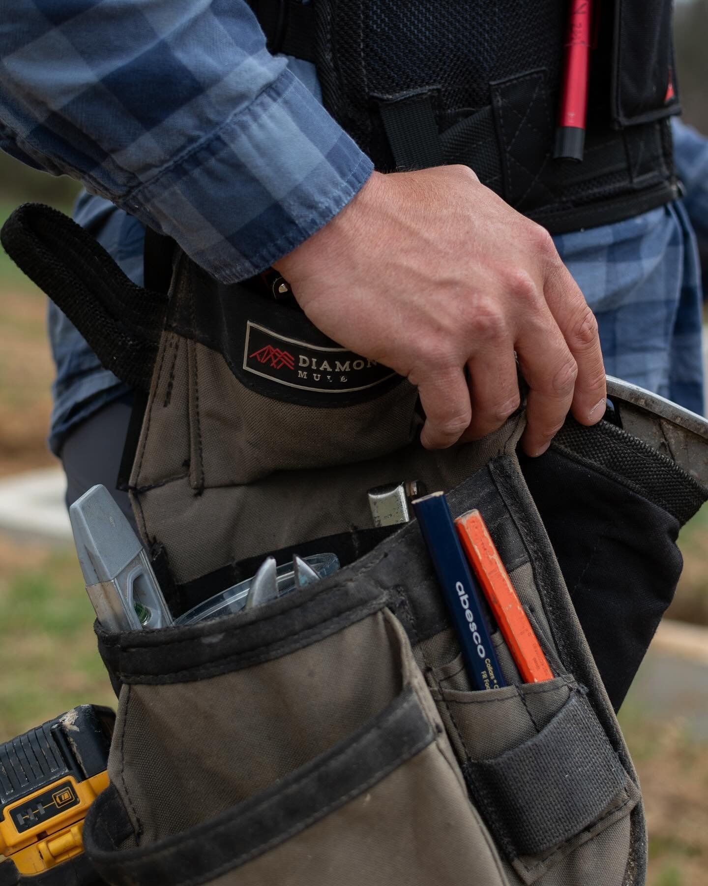 A man is holding a tool belt with tools in it.