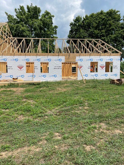 A house is being built in a grassy field.
