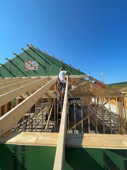 A man is working on the roof of a house under construction.
