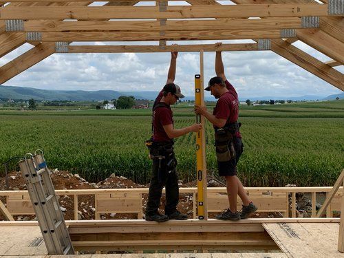 Two men are working on a wooden structure in a field.