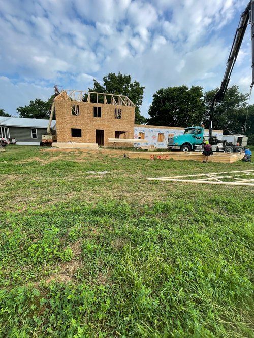 A large house is being built in a grassy field.