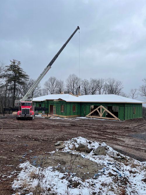 A crane is lifting a roof of a house under construction.