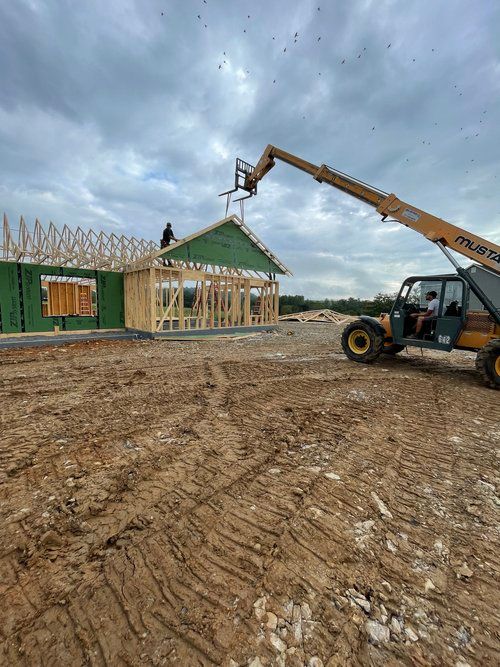 A forklift is lifting a piece of wood on top of a house under construction.