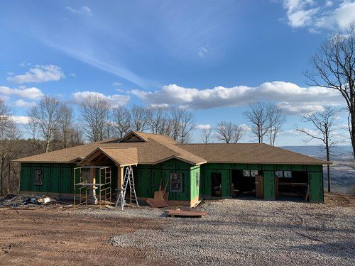 A large house is being built on top of a dirt hill.