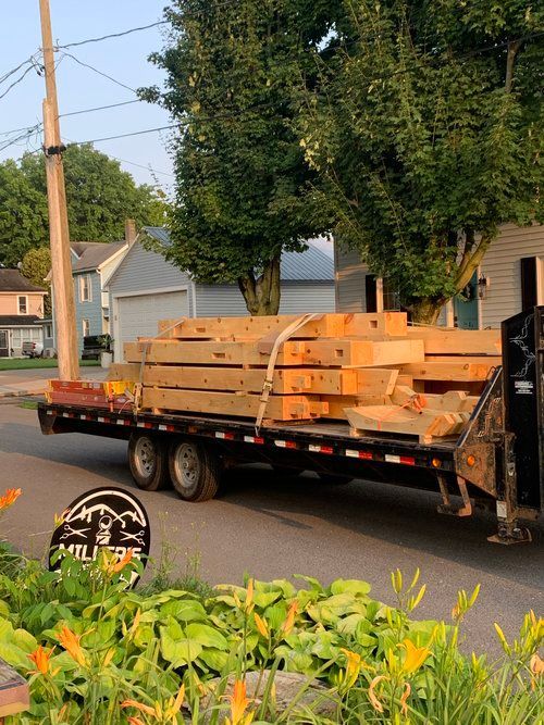 A truck is carrying a load of wood on a trailer.