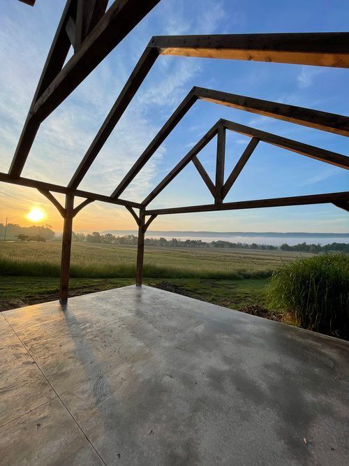 A wooden structure with a view of a field and a body of water.