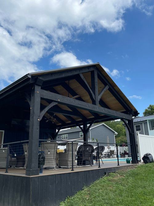 A large wooden pavilion with a wooden roof is sitting next to a pool.