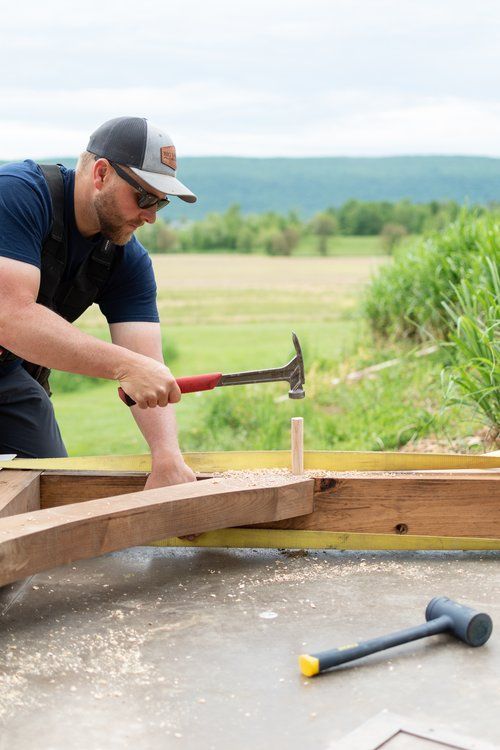 A man is hammering a nail into a piece of wood.