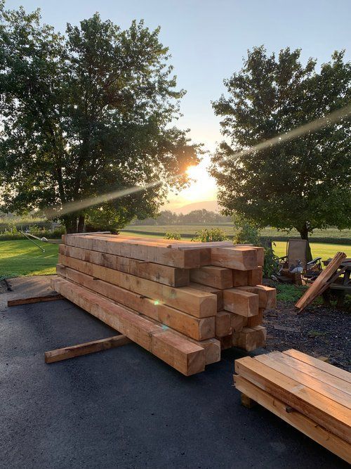 A pile of wood is sitting on the ground in front of a field.