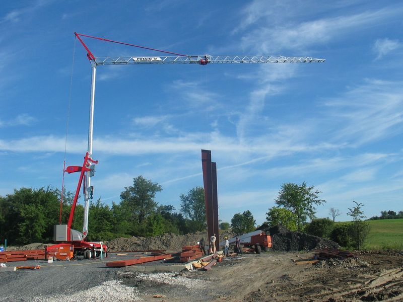 Construction crane at work, lifting materials on a sunny day.