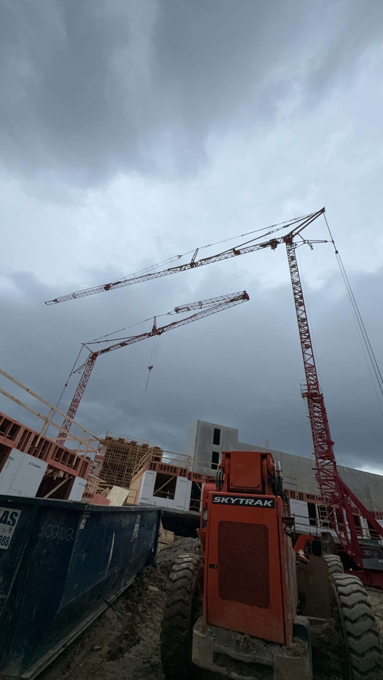 Construction site with cranes under a cloudy sky.