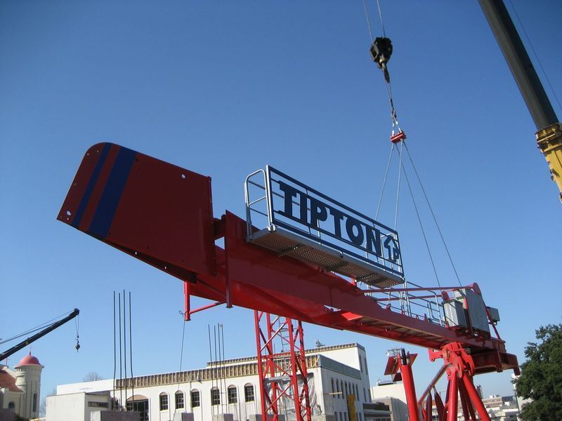 Red crane lifting a sign for 