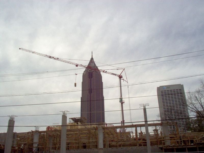 Construction site with cranes, tall buildings, and cloudy sky.