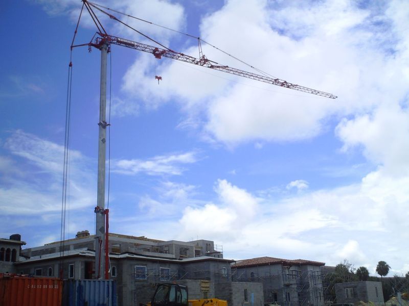 Construction crane over a building, blue sky with clouds.