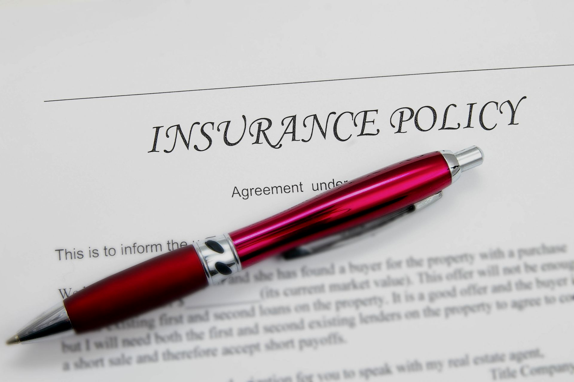 Red pen resting on an insurance policy document.