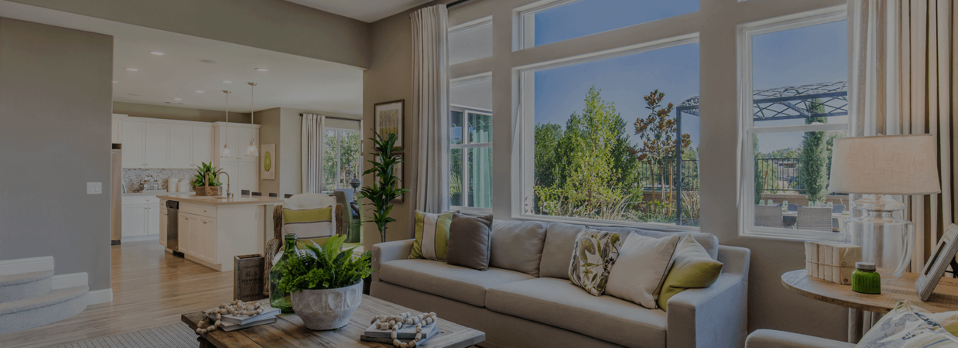 Bright living room with large windows, beige sofa, indoor plants, and a view of trees outside