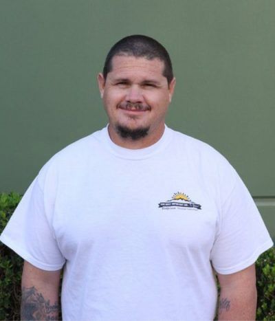Smiling man in a white T-shirt standing against a green wall