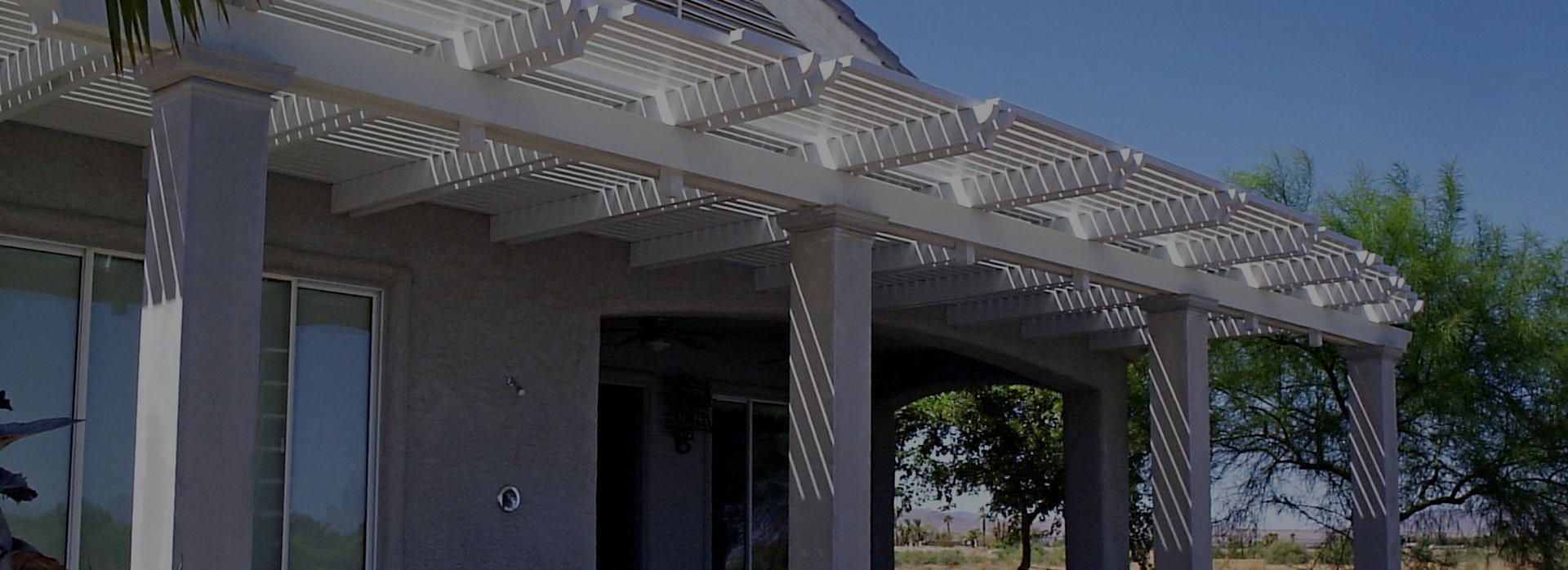 Covered outdoor patio with white lattice pergola, brick columns, and shaded seating area